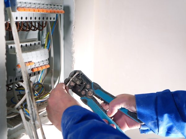 Electrician works with internet cable conneting. Electrical switchboard with automats and wires.